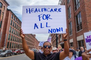 Man holding a sign that reads "healthcare for all now!"