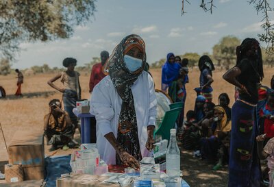 Photo of service provider in rural area, with mask and medical supplies