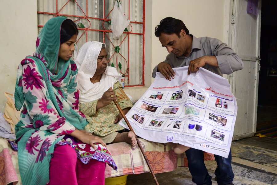man showing women a board for the National Need based assessment survey on assistive technology