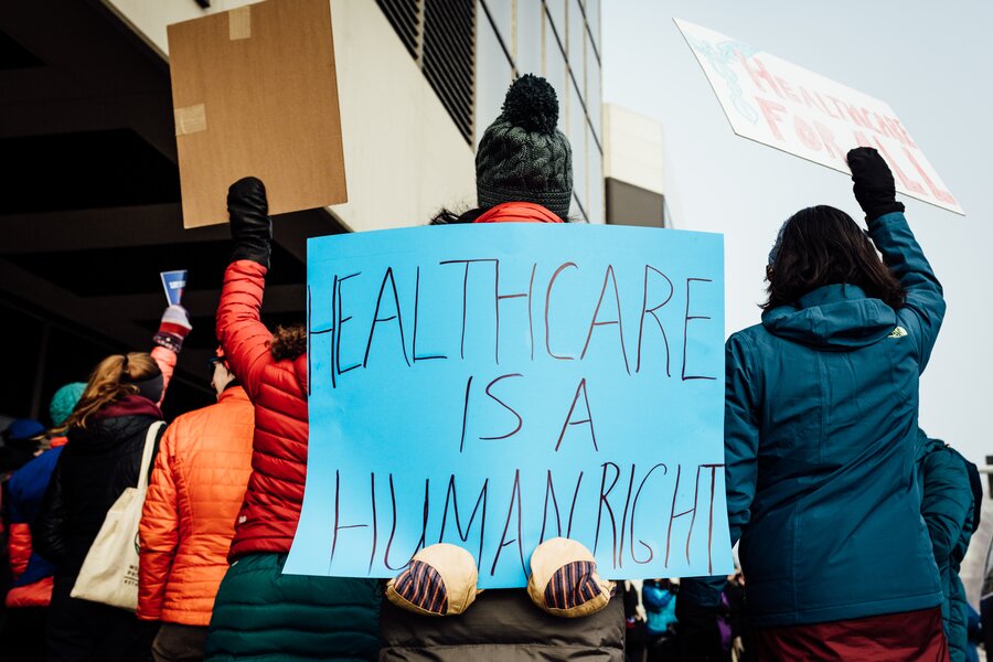 Photo of protesters with sign reading "healthcare is a human right"