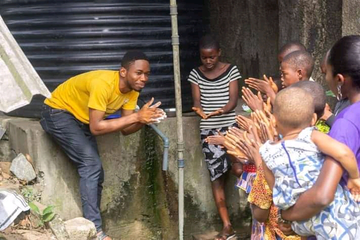 Photo of Archibong Bassey teaching hand washing to a group of children